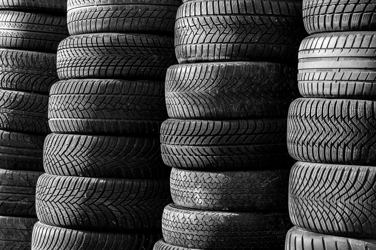 Black and white image of stacked vehicle tires showcasing various tread patterns.